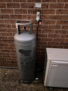 Air conditioning compressor next to gas bottle